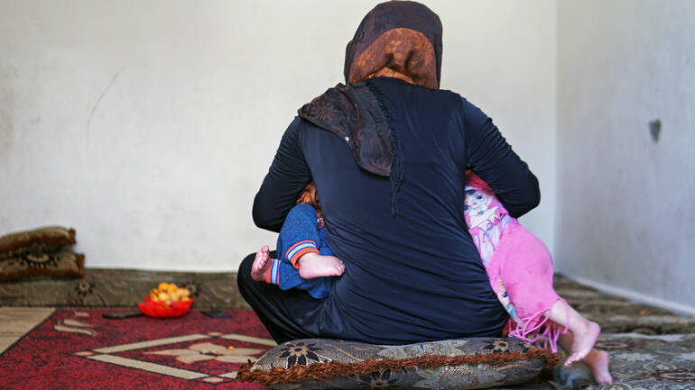 Dana füttert ihre Zwillinge Nagham (11 Monate) und Akram (11 Monate) gleichzeitig in ihrem Haus in der Sammelunterkunft im Südlibanon im Mai 2022.