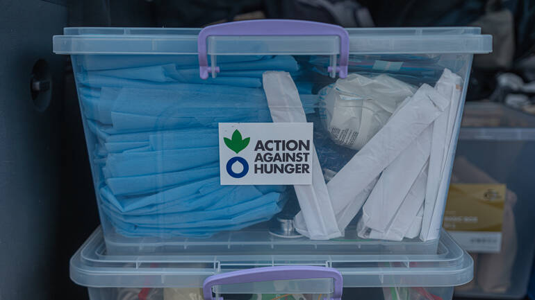 Kiste mit medizinischen Hilfsmitteln und Aktion-gegen-den-Hunger-Logo)