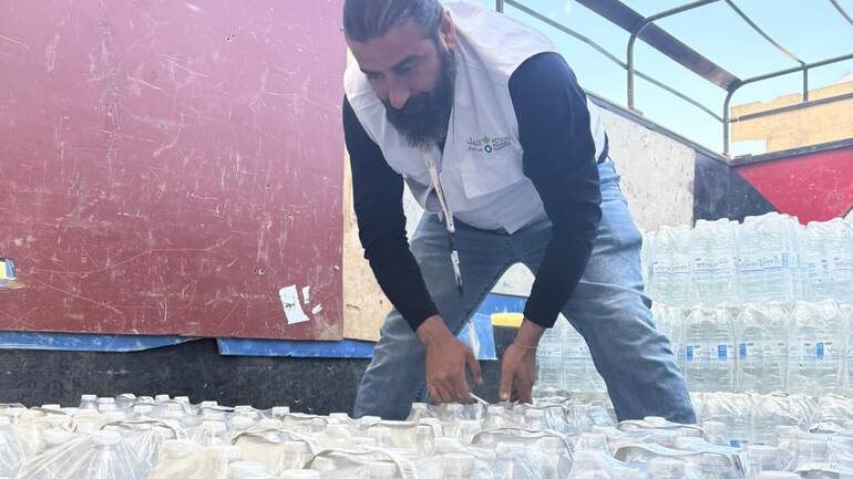 Mitarbeiter von Aktion gegen den Hunger liefert Flaschen mit sauberem Wasser