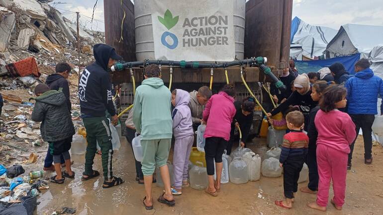 Kinder füllen Wasserkanister an einem Tanklaster mit frischem Trinkwasser in Gaza auf.