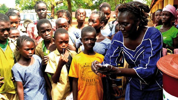 Frau erklärt in Guinea den umstehenden Menschen etwas.