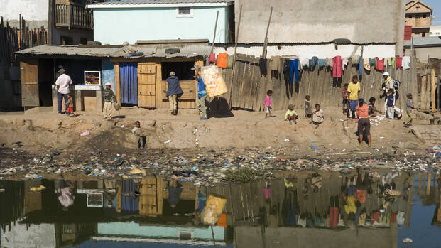 Menschen in Madagaskar an vermülltem Fluss.