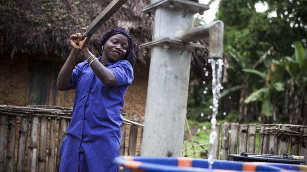 Frau in Sierra Leone betätigt Wasserpumpe.