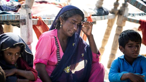 Seema aus Pakistan mit ihren beiden Kindern. Bei den Überschwemmungen haben sie ihr Zuhause verloren und sind nun der Hitze ausgesetzt.