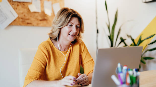 Eine Frau nimmt mit ihrem Laptop an einem Online-Vortrag teil.